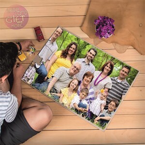 May include: A family photo puzzle featuring a group of people of different ages, smiling and posing outdoors. The puzzle is made of wood and has a light brown finish.