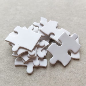 May include: A pile of white puzzle pieces, some are stacked on top of each other.