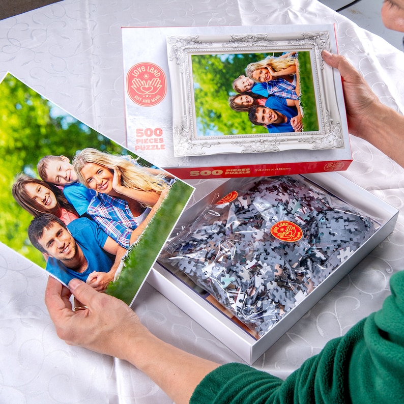 May include: A white box with a 500 piece jigsaw puzzle of a family. The box has a picture of the family on the front and the words "Love London But And More" on the side. The puzzle pieces are in a plastic bag inside the box.