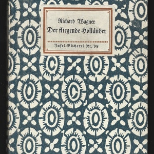 Puede incluir: Una cubierta de libro azul con un patrón blanco de círculos y flores. El título "Richard Wagner Der fliegende Holländer" está impreso en la cubierta, junto con el texto "Insel-Bücherei Nr. 98".