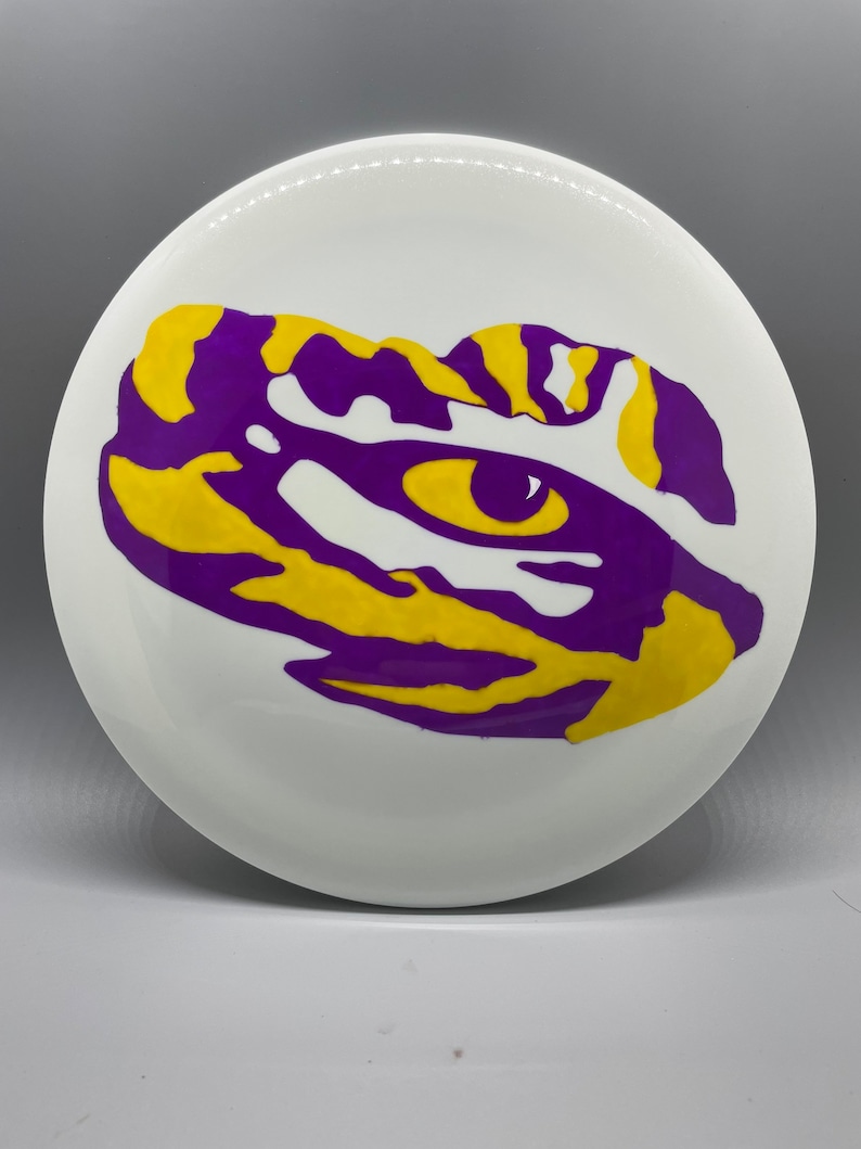 May include: A white ceramic plate with a purple and yellow tiger eye design.