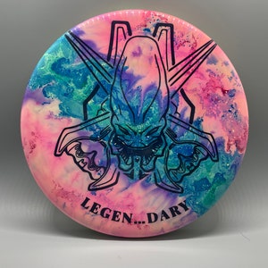 May include: A pink, blue, and green disc with a black alien-like creature graphic and the text "LEGEN...DARY".