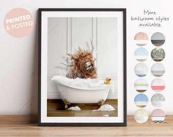 May include: A Highland cow with long, shaggy brown fur is taking a bath in a white bathtub. The cow is looking at the camera with a surprised expression. There is a yellow rubber duck in the bathtub with the cow. The background is a white tiled bathroom wall.