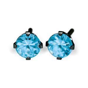 May include: A pair of stud earrings featuring round, light blue gemstones set in black metal. The gemstones have a faceted appearance, reflecting light. The earrings are displayed against a white background.
