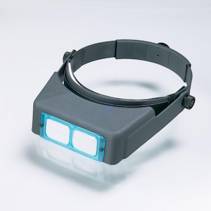 May include: A gray headband magnifier with two blue lenses. The headband is adjustable and has a black plastic knob on the side.