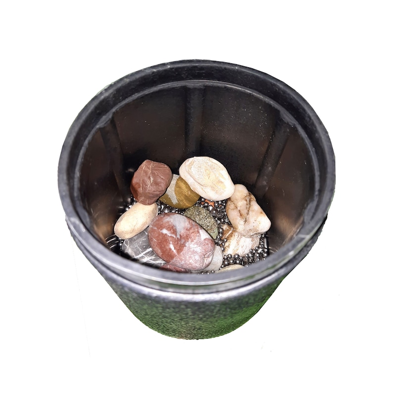 Puede incluir: Un recipiente de pl&aacute;stico negro lleno de peque&ntilde;as cuentas met&aacute;licas redondas, lisas y plateadas, as&iacute; como piedras de varios colores. Las piedras son marrones, rojas y blancas.