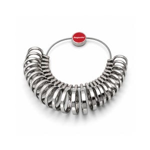 May include: A silver-coloured metal ring sizer set featuring a circular wire cable holding multiple individual ring bands of varying sizes. A small red circular tag with the white text Augusta is attached to the top of the wire cable.
