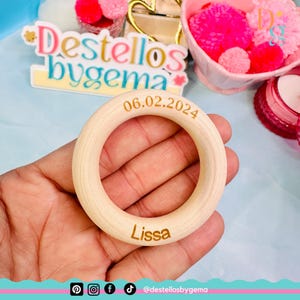 Puede incluir: Un anillo de madera con el nombre "Lissa" y la fecha "06.02.2024" grabados en él. El anillo está en una mano.