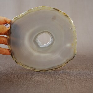 May include: A grey agate slice with a hole in the centre. The agate has a natural, polished finish.