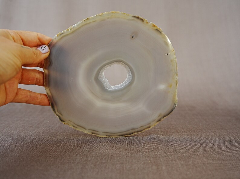 May include: A grey agate slice with a hole in the centre. The agate has a natural, polished finish.