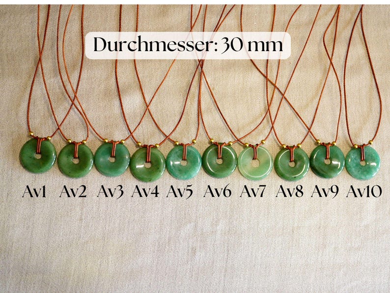May include: Ten jade pendant necklaces with a circular design and a brown cord. The pendants are a vibrant green color and are labeled Av1 through Av10. The text "Durchmesser: 30 mm" is displayed above the necklaces.