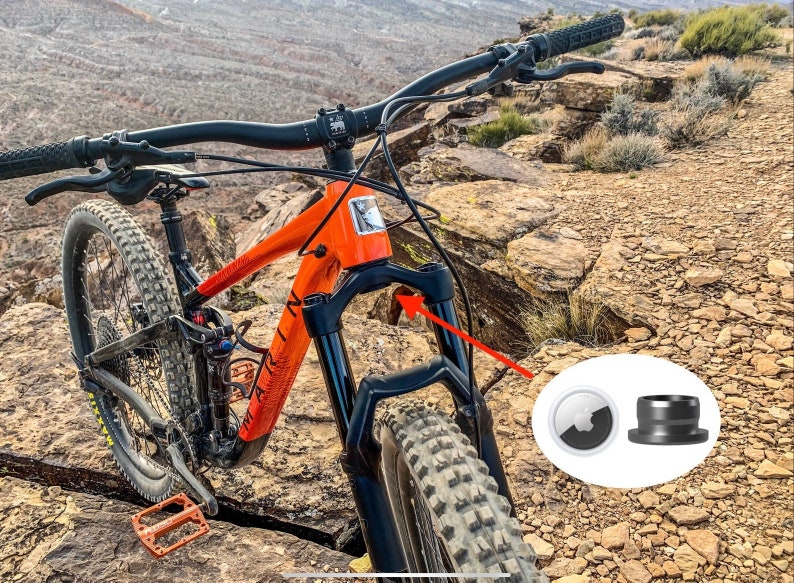 K&ouml;nnte beinhalten: Nahaufnahme eines schwarzen Mountainbikes mit orangefarbenem Rahmen. Das Fahrrad befindet sich auf einem felsigen Weg. Das Bild zeigt auch zwei schwarze und wei&szlig;e Fahrrad-Steuersatzkappen.