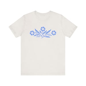 May include: A white t-shirt with a blue floral design on the front.