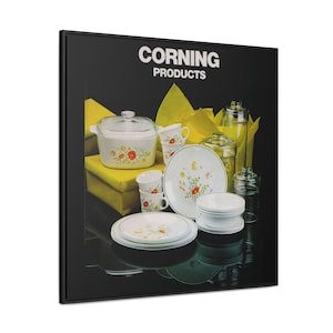 May include: A black and white image of Corning Products kitchenware. The image features a variety of dishes, including a casserole dish, plates, bowls, and mugs. The dishes are decorated with a floral pattern in shades of yellow, orange, and red. The image also includes a yellow box with the Corning Products logo.