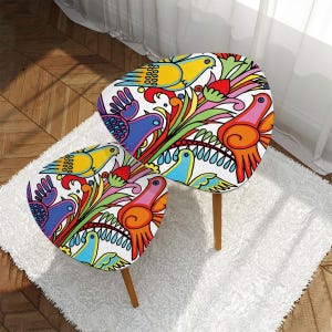 May include: Two nesting tables with a white base and wooden legs. The tabletops feature a colorful, whimsical design of birds and flowers.