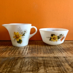 Może przedstawiać: Biały zestaw dzbanka do śmietanki i cukiernicy z kwiatowym wzorem z żółtymi i białymi kwiatami. Wzór znajduje się na białym tle.