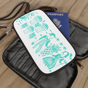 May include: A white passport holder with a teal design of stylized figures and flowers. The holder has a black zipper and a black strap. The word "PASSPORT" is printed on a blue passport.