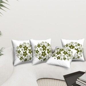 May include: Four white throw pillows with a green floral pattern. The pillows are arranged on a white couch.
