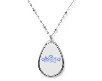 Puede incluir: Un collar de cadena de plata con un colgante en forma de lágrima que presenta un diseño floral azul sobre un fondo blanco.