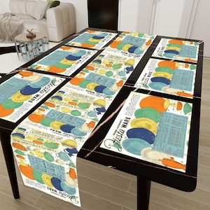 Puede incluir: Una mesa negra con un mantel blanco con un patrón vintage de Fiesta Ware. El mantel tiene un patrón repetitivo de platos, tazones y tazas coloridos con el texto "Fiesta Ware" impreso en cada pieza.