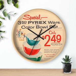 Puede incluir: Un reloj vintage con un anuncio de los años 50 para un juego de cuencos de color Pyrex Ware de 350 piezas. El anuncio muestra a una mujer y una niña sosteniendo un juego de tres cuencos encajables en azul, rojo y verde. La esfera del reloj dice "Solo 2,49 € Ahorra 1,01 € ¡Oferta por tiempo limitado!"