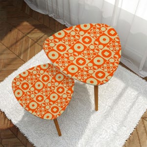 May include: Two nesting tables with a geometric pattern of orange and cream circles and squares. The tables have a unique, asymmetrical shape and wooden legs.