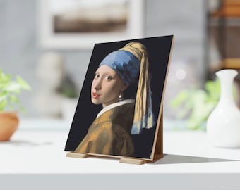 May include: A wooden print of Johannes Vermeer's "Girl with a Pearl Earring" painting. The artwork features a young woman with a blue and yellow headscarf, a pearl earring, and a mustard-colored jacket. The print is displayed on a wooden stand.