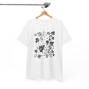 Puede incluir: Camiseta blanca con un estampado en blanco y negro de grosellas y hojas.