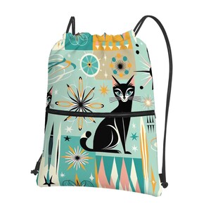 Op de afbeelding: Een turquoise blauwe trekkoordtas met een zwarte kat en retro geometrische patronen. De tas heeft een zwart ritsvak en zwarte trekkoorden.