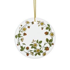Pode incluir: Ornamento de cerâmica branca com uma coroa de folhas verdes, flores brancas e morangos vermelhos.