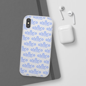 May include: A clear phone case with a white background and a blue floral pattern. The case is designed for a smartphone with a dual camera lens.