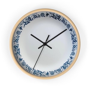 May include: A white clock with a blue and white floral design around the edge. The clock has black hands and a wooden frame.