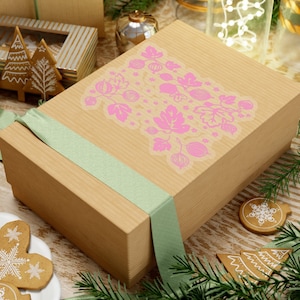 May include: A brown gift box with a green ribbon and a pink floral design. The design features a repeating pattern of pink flowers and leaves.