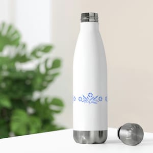 May include: White stainless steel water bottle with a blue floral design around the middle. The bottle has a silver lid.