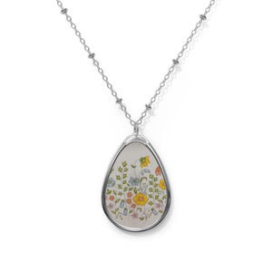 May include: A silver chain necklace with a teardrop-shaped pendant featuring a floral design in shades of yellow, blue, green, and pink.