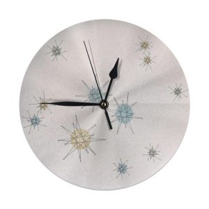 May include: A white round clock with black hands and a white background with a pattern of blue and yellow stars.