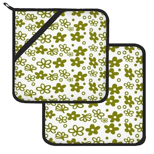 May include: A white kitchen set with an olive green floral pattern. The set includes a pot holder and an oven glove, both with black trim. The floral design features various flower shapes and sizes.