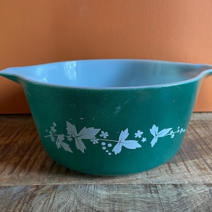 May include: A green and white mixing bowl with a floral design. The bowl is made of ceramic and has a smooth, glossy finish.