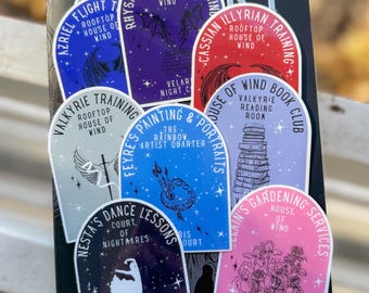 Könnte beinhalten: Eine Sammlung farbenfroher Aufkleber mit verschiedenen Designs und Texten, darunter "Azriel Flight", "Rhysand Literacy" und "Cassian Illyrian Training". Die Aufkleber sind in Blau-, Lila-, Rot- und Rosatönen gehalten und zeigen Illustrationen von Flügeln, Büchern und anderen Fantasy-Elementen.