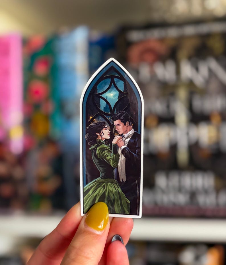 May include: A sticker depicting a romantic scene of a couple in formal wear, framed by a gothic window with a moonlit cityscape. The woman is in a green gown, and the man wears a tuxedo. The sticker has a white border.
