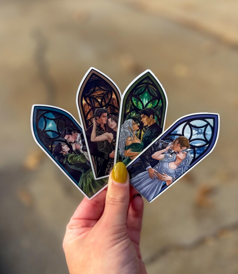 May include: Four stickers with romantic illustrations in stained-glass window frames. Each sticker shows a couple embracing, with different colour schemes and designs. The stickers are held in a hand with yellow nail varnish.