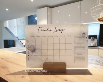 May include: A white dry-erase board with a floral design and the text "Familie Luongo". The board is divided into a weekly calendar with spaces for each day of the week, a to-do list, a meal planner, and a birthday list.