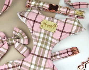 May include: A pink, brown, and white plaid dog harness, collar, leash, and bow tie set. The set includes a harness, collar, leash, and bow tie. The harness has a leather tag that says "Peonies". The hardware is rose gold.