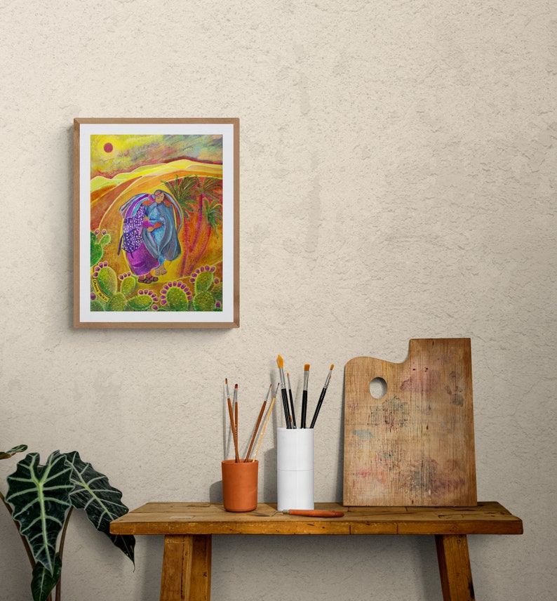 May include: A framed painting depicting two figures walking through a desert landscape. The figures are wearing colourful clothing and carrying a basket of purple fruit. The background is a yellow and orange desert with a bright orange sun in the sky.