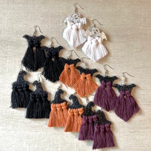 May include: A set of ten witch hat earrings with black, purple, and orange tassels. The earrings are made of glitter and have a silver hook closure.