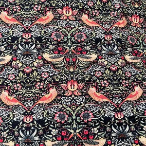 May include: A black fabric with a repeating pattern of stylized birds, flowers, and leaves. The pattern is in shades of pink, green, and white.