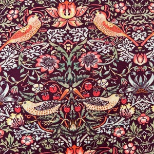 May include: A burgundy fabric with a repeating pattern of stylized birds, flowers, and leaves. The birds are orange and yellow with black accents. The flowers are pink and orange with yellow centers. The leaves are green and brown.