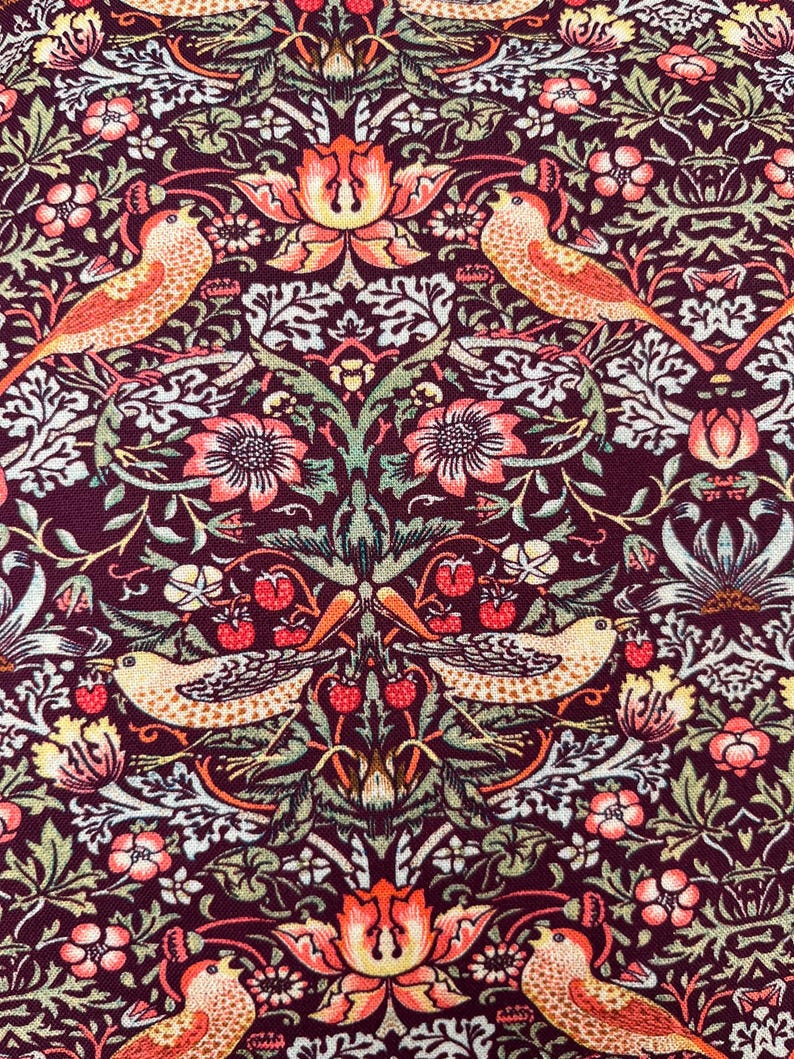 May include: A burgundy fabric with a repeating pattern of stylized birds, flowers, and leaves. The birds are orange and yellow with black accents. The flowers are pink and orange with yellow centers. The leaves are green and brown.