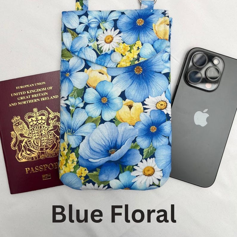 May include: A blue floral phone case with a pocket, featuring a pattern of blue flowers, yellow buds, and white daisies. A passport and a black smartphone are next to the case. The text "Blue Floral" is at the bottom.
