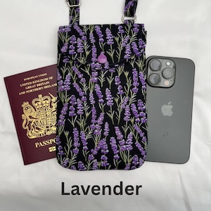 Puede incluir: Un bolso bandolera negro para tel&eacute;fono con un estampado floral de lavanda, un bot&oacute;n morado y correas ajustables. La palabra "Lavender" est&aacute; impresa en la parte inferior. Un pasaporte y un smartphone est&aacute;n al lado del bolso.